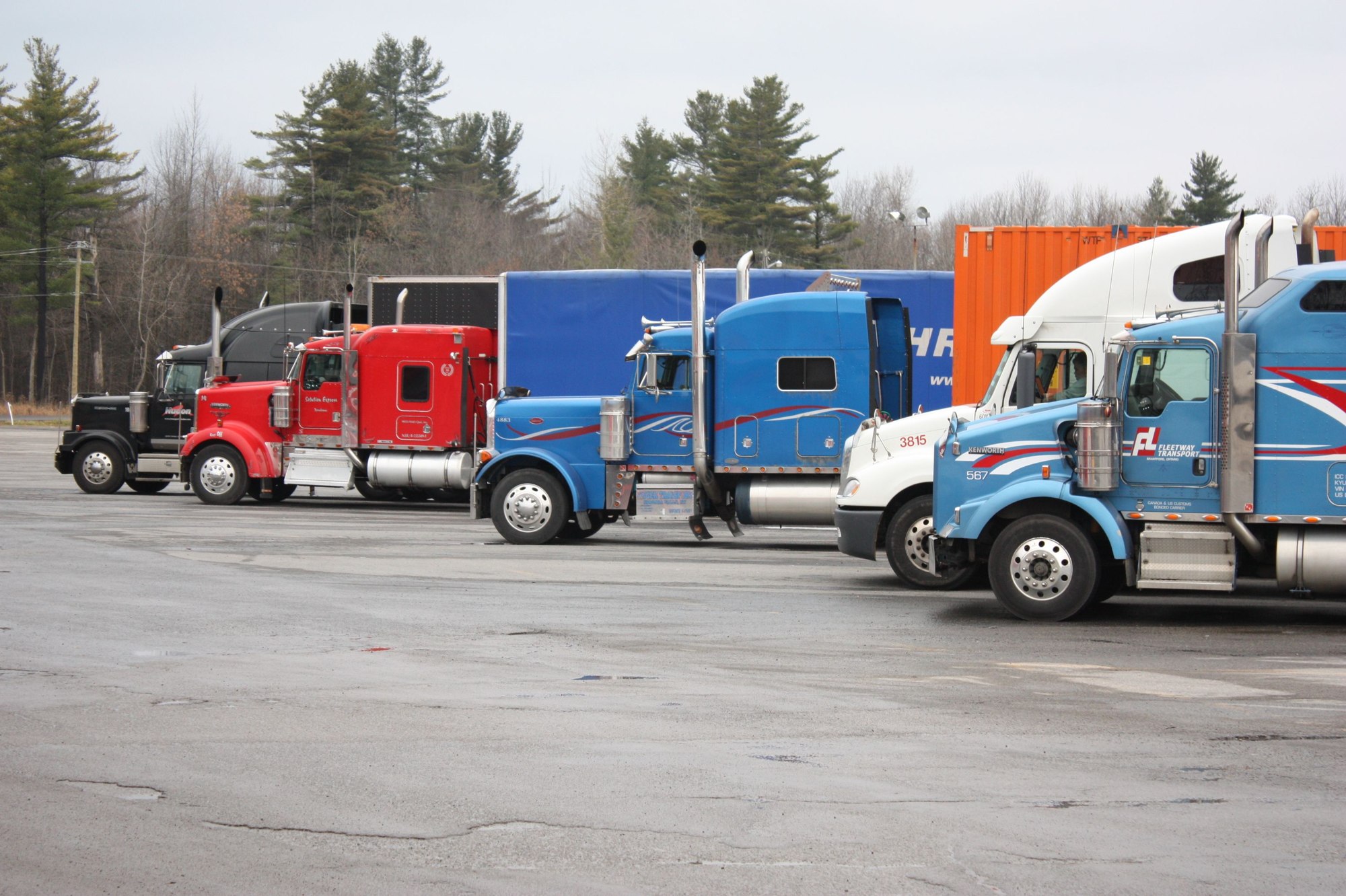 Conventional semi trucks parked in an open freight yard